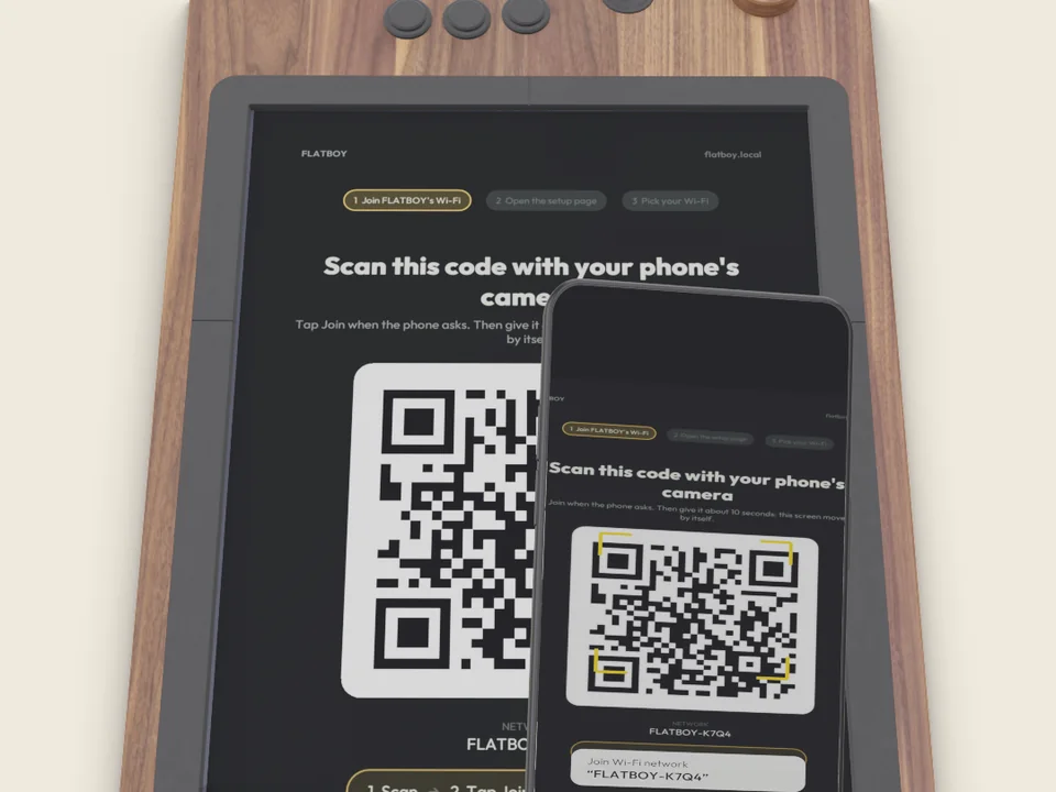 A phone held over FLATBOY's screen, scanning the setup code