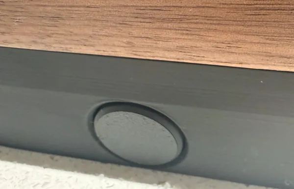 A flipper button in the black side, under the walnut edge